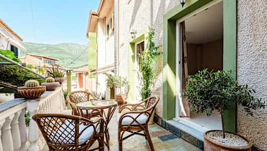 Terrass med korgmöbler, växter och utsikt mot grönskande berg. (AI-genererad text)