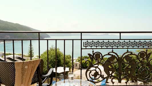 Utsikt från en balkong med dekorativt räcke över hav och kust. (AI-genererad text)