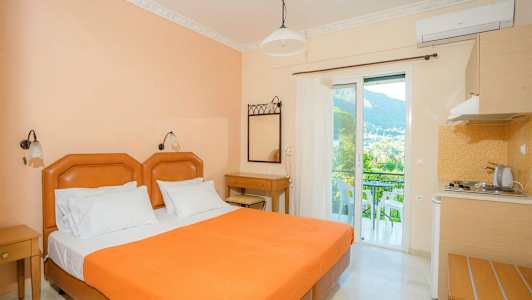 Hotellrum med en orange säng, skrivbord och balkong med utsikt. (AI-genererad text)