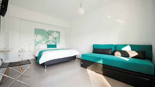 Ett hotellrum med en säng och en soffa, inrett i ljusa färger. (AI-genererad text)