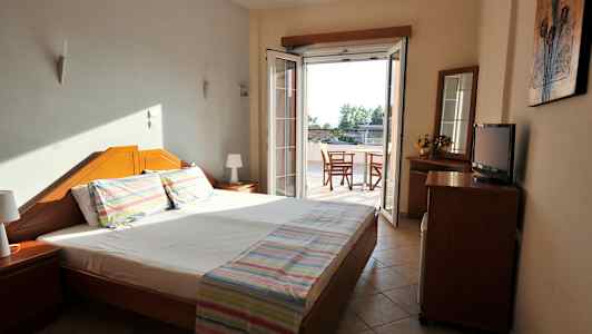 Ett hotellrum med en dubbelsäng och en dörr mot en balkong. (AI-genererad text)