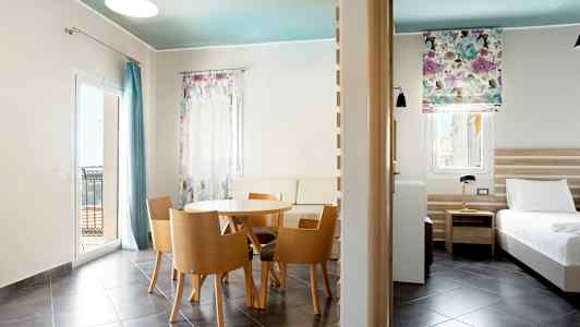 Modernt inredd hotellrum med matsalsbord, sittplatser och bädd. (AI-genererad text)