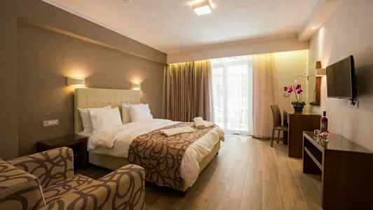 Ett hotellrum med säng, fåtölj, skrivbord och TV. (AI-genererad text)