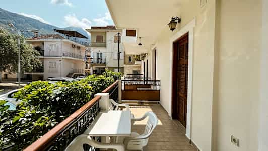 Balkong med bord och stolar samt utsikt över ett bostadsområde med hus. (AI-genererad text)