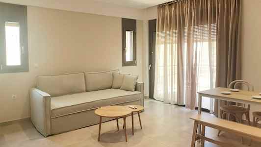 En sittgrupp med soffa, bord och matbord. Fönster med gardiner i bakgrunden. (AI-genererad text)