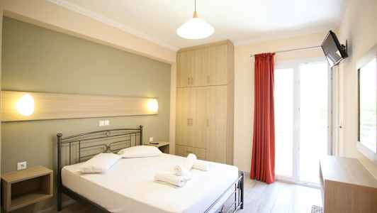 Ett ljust hotellrum med en säng, skåp och en balkongdörr. (AI-genererad text)