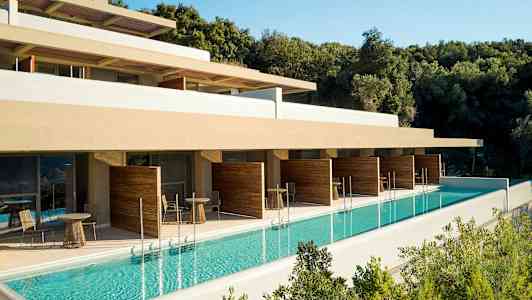 Utomhuspool vid hotellbyggnad med terrass och avskärmade sittgrupper. (AI-genererad text)