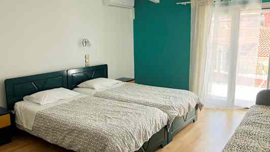 Ett hotellrum med två enkelsängar, en soffa och en balkongdörr. (AI-genererad text)