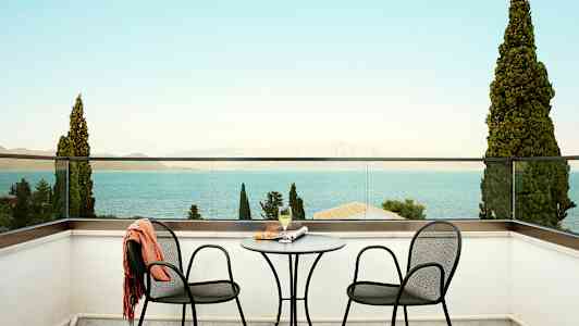 Två stolar och ett bord på en terrass med utsikt över havet. (AI-genererad text)