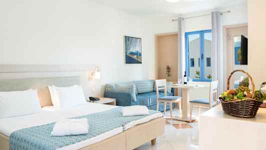 Ett hotellrum med dubbelsäng och sittgrupp. En korg med frukt står på ett bord. (AI-genererad text)