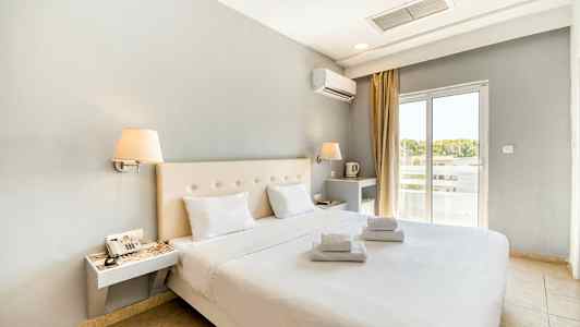 Modernt möblerat hotellrum med dubbelsäng och vita lakan. Fönster med ljusinsläpp. (AI-genererad text)