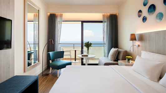 Hotellrum med havsutsikt, soffa, sittplats och säng. (AI-genererad text)