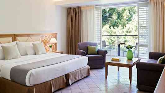 Interiör av hotellrum med dubbelsäng, sittgrupp och balkong. (AI-genererad text)