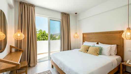 Rum med en dubbelsäng, en skrivbordshörna och ett fönster som leder till en balkong. (AI-genererad text)