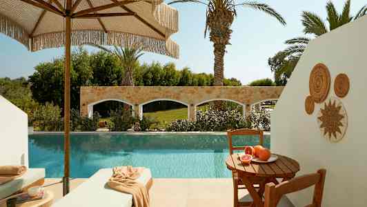 Uteplats med pool, solstolar och ett bord med färska frukter. (AI-genererad text)