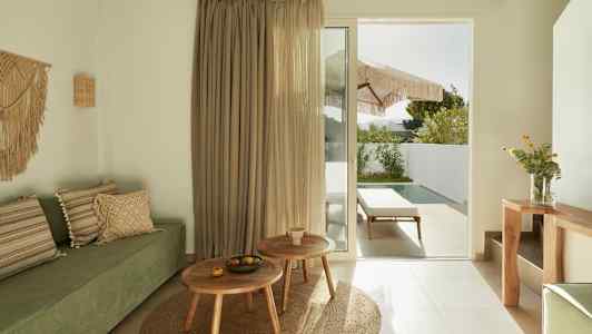 Modernt rum med grön soffa, trämöbler och en glasdörr som leder till en uteplats med pool. (AI-genererad text)