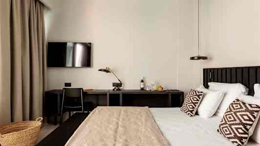 Ett hotellrum med en säng, skrivbord och TV. (AI-genererad text)