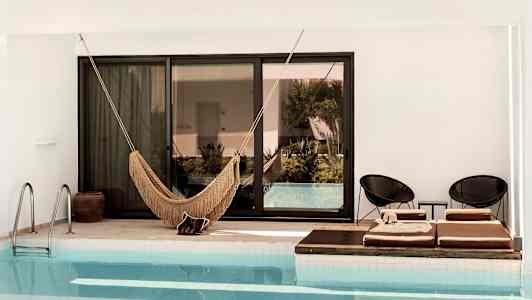 Bild av en pool med en hängmatta och solstolar vid kanten. (AI-genererad text)