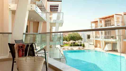 Vy från balkong mot en modern byggnad och poolområde. (AI-genererad text)