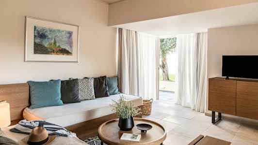 Ett modernt inrett vardagsrum med en soffa, soffbord, TV och stora glasdörrar som leder ut. (AI-genererad text)