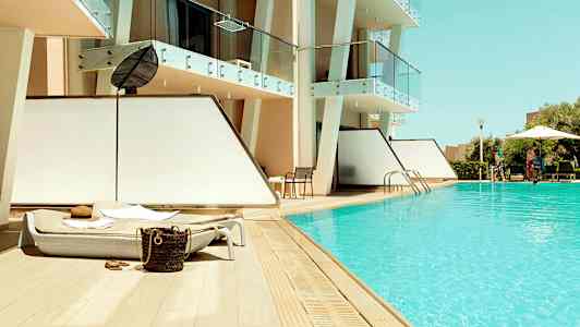 Utomhuspool med solstolar vid ett modernt hotell. (AI-genererad text)