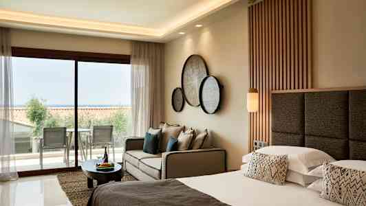 Bild av ett modernt hotellrum med dubbelsäng, soffa och utsikt mot en balkong. (AI-genererad text)