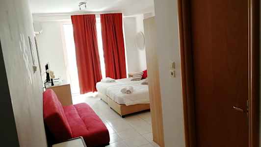 Ett hotellrum med en bäddad säng, röda gardiner och en röd soffa. (AI-genererad text)