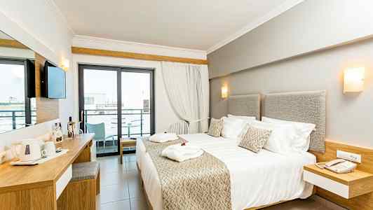 Modernt hotellrum med dubbelsäng, skrivbord och balkong. (AI-genererad text)