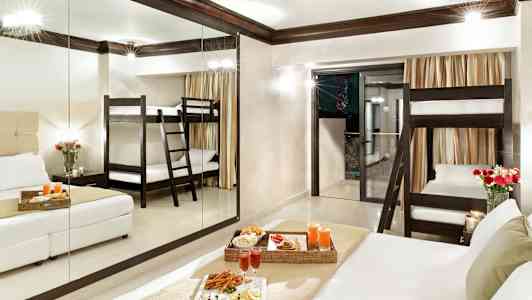 Hotellrum med en våningssäng, dubbelsäng och serverad måltid. (AI-genererad text)