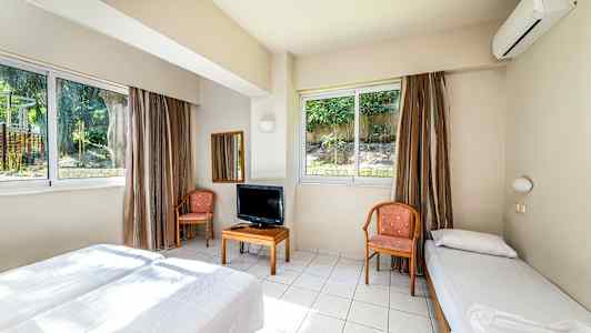 Ett hotellrum med två sängar, stolar, ett bord med TV och stora fönster. (AI-genererad text)