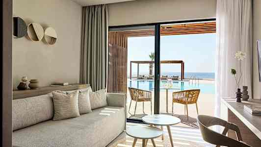 Ljusa vardagsrumsmöbler med utsikt över pool och hav. (AI-genererad text)