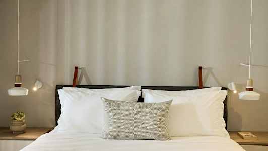 En säng med kuddar och upplysta lampor på båda sidor. (AI-genererad text)