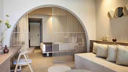 Modernt hotellrum med sittgrupp och avdelare mot sovutrymme. (AI-genererad text)