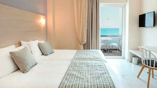 Hotellrum med två sängar, havsutsikt från balkong. (AI-genererad text)