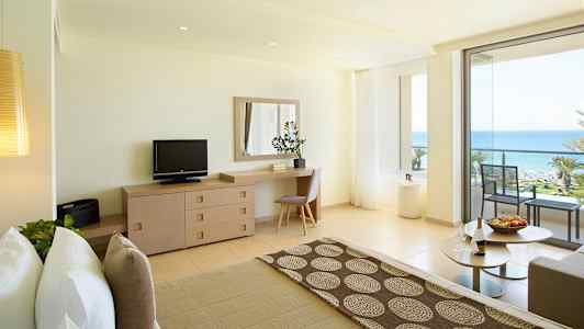 Ljust hotellrum med havsutsikt och balkong. (AI-genererad text)