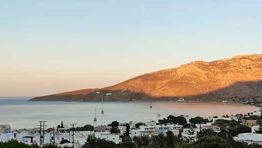 Strandstad med segelbåtar och berg i bakgrunden. (AI-genererad text)