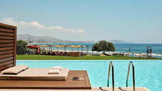 Vy från en pool med utsikt mot havet, solstolar och parasoller. (AI-genererad text)