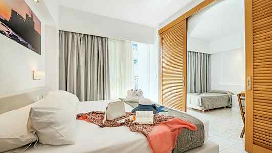 Ett hotellrum med två sängar, dekorerat med personliga föremål på den främre sängen. (AI-genererad text)