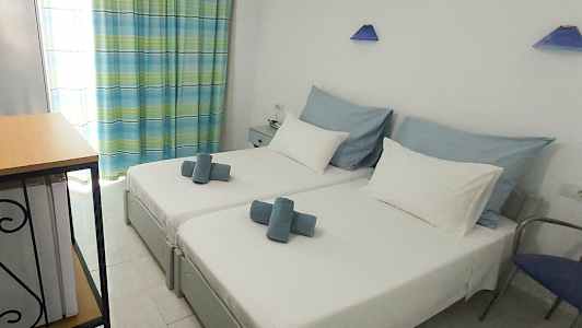 Bild av ett hotellrum med två enkelsängar, vit sängklädsel och blå dekoration. (AI-genererad text)