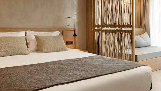 En hotellrumsinteriör med en bäddad säng och en avskiljande dekorativ träram. (AI-genererad text)