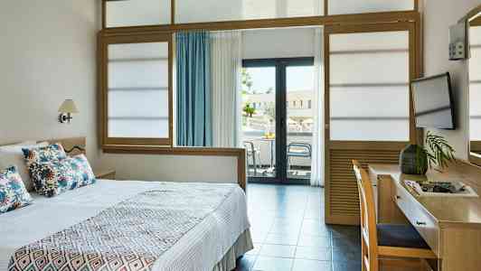 Hotellrum med en säng, skrivbord och balkong. (AI-genererad text)