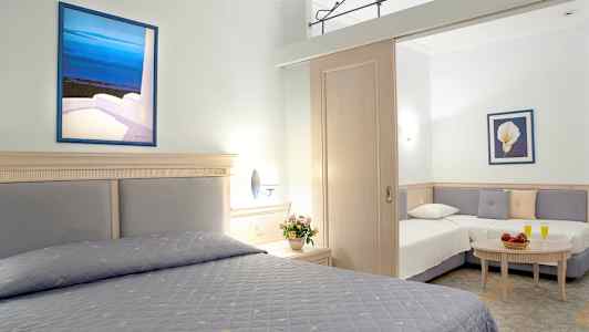 Ett hotellrum med två sängar och en soffhörna, dekorerat med blomster och målningar. (AI-genererad text)