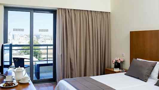 Ett hotellrum med stor säng, kaffekoppar på ett bord och en balkong med utsikt. (AI-genererad text)