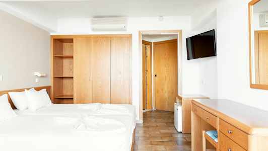 Hotellrum med två enkelsängar, garderob, skrivbord och spegel. (AI-genererad text)