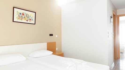 Ett hotellrum med två sängar, ett nattduksbord och en målning på väggen. (AI-genererad text)