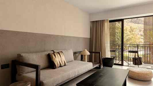 Ett vardagsrum med soffa, soffbord, och stora fönster som vetter mot en balkong. (AI-genererad text)