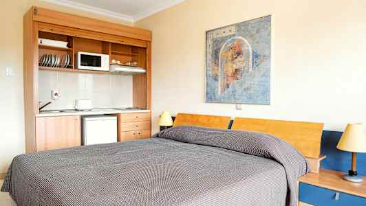 Ett rum med en säng, ett mindre kök och en väggmålning. (AI-genererad text)