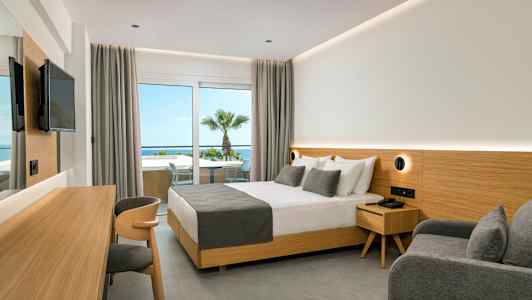 Hotellrum med dubbelsäng, grå inredning och utsikt mot havet. (AI-genererad text)