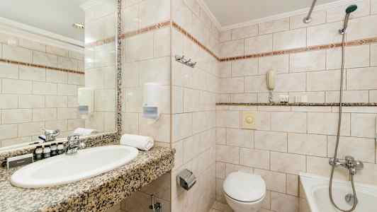 Bild av ett badrum med tvättställ, spegel, toalett och badkar. (AI-genererad text)