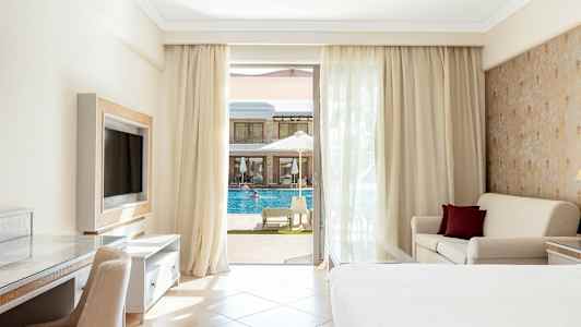 Hotellrum med balkong, säng, soffa och utsikt mot en pool. (AI-genererad text)